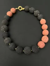 Collar de piedras volcánicas naturales con diseño de esferas texturizadas en tonos rosado y gris oscuro, dispuestas de forma asimétrica.