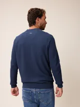 Sweater de punto color negro, con cuello alto y cierre frontal parcial tipo medio cierre. Presenta textura en el tejido y logo bordado en el pecho.