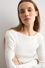 Remera de manga larga en color blanco, con escote bote y corte ajustado al cuerpo.