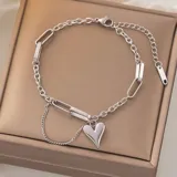 Pulsera plateada con eslabones tipo clip y cadena, con dije de corazón colgante.