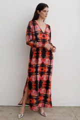 Vestido largo de corte recto con escote en V y mangas largas. Presenta un estampado abstracto en tonos rojos, naranjas y negros, con tajos laterales en el ruedo.