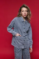 Sobrecamisa de jean de calce relajado color gris, con solapa clásica, bolsillos frontales y cierre de botones metálicos.