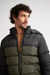 Campera puffer de nylon con diseño bicolor en negro y verde oliva. Cuenta con cierre frontal completo, capucha desmontable y logo de la marca estampado en el pecho.