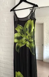 Vestido largo de microtul negro con estampado de flores grandes en tonos verdes. Presenta breteles finos, escote redondo y diseño ajustado al cuerpo con transparencias.