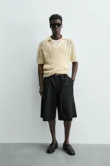 Bermuda negra de corte ancho (wide fit) con pliegues frontales, bolsillos laterales y bolsillos traseros de vivo.