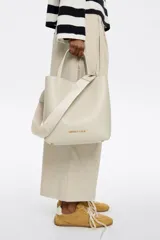 Bolso tote Bimba y Lola modelo Chihuahua, color beige, con doble asa corta y correa larga extraíble con logo de la marca.