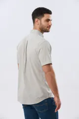 Camisa de manga corta confeccionada en mezcla de lino y algodón, con estampado de cuadros pequeños en tonos azules. Presenta cuello camisero con botones, cierre frontal abotonado, bolsillo aplicado en el pecho y dobladillo redondeado.