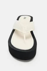 Sandalias de plataforma color negro, con diseño de tira de dedo y suela alta tipo cuña.