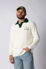 Sweater de punto con textura waffle en color blanco, con cuello polo en contraste color verde oscuro y cierre frontal de botones. Presenta un bordado decorativo en el pecho y un corte relajado.