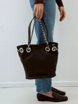 Bolso tipo tote de cuero negro con doble asa, una de cuero y otra de cadena plateada.