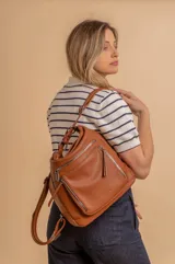 Cartera mochila versátil de cuero sintético con textura granulada, color negro. Cuenta con múltiples bolsillos frontales con cierre, correas ajustables que permiten su uso tanto como cartera de hombro o como mochila, y herrajes metálicos.