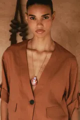 Chaqueta corta de escote en pico con cierre frontal de un botón. Presenta mangas cortas con detalle de vuelta, trabilla y botón, además de falsos bolsillos delanteros con solapa.