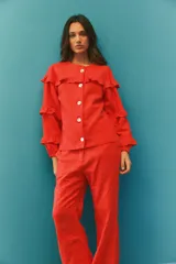 Campera de algodón y lino color rojo, con diseño de volados en el frente y mangas. Presenta cuello redondo, cierre frontal con botones y mangas largas con puños elásticos.