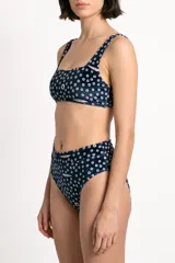 Top de bikini azul marino con estampado de círculos y pequeños peces, de escote cuadrado y tirantes anchos.