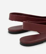 Zapatilla tipo slingback de cuero color marrón oscuro, con diseño de punta fina y talón descubierto con tira de ajuste.
