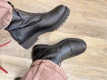 Botas de cuero color marrón con diseño estilo brogue, cierre lateral y suela track negra de goma resistente.