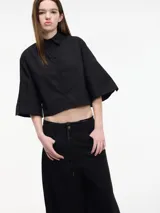 Camisa cropped negra con botones frontales y mangas 3/4 acampanadas.