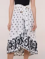 Vestido midi combinado de corte fluido. Presenta un torso ajustado acanalado sin mangas, con cuello redondo y sisas clásicas. Cuenta con cintura elastizada con lazo para anudar y falda evasé con estampado floral y geométrico, finalizando con un volante en el ruedo.
