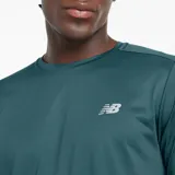 Remera de manga larga New Balance, color verde azulado, con cuello redondo y logo reflectante en el pecho. Confeccionada en tejido transpirable y ligero, con dobladillo trasero más bajo y aberturas laterales.