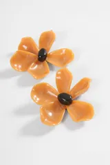 Aros de acrílico en forma de flor color beige con centro negro.