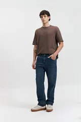 Pantalón de jean corte regular con tiro medio, diseño clásico de cinco bolsillos, cierre frontal con botón y bragueta, y pasacintos en la cintura.