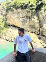 Remera blanca de algodón con cuello redondo y estampado en la espalda con imágenes de cogollos de marihuana y texto "BROKERS HIGH QUALITY GOODS".