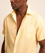 Camisa de manga corta confeccionada en mezcla de lino y algodón, con cuello inglés, cierre frontal de botones y bolsillo en el pecho. Presenta un corte comfort holgado y diseño liso.