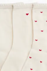 Pack de cinco pares de medias de caña media, color blanco roto, confeccionadas en tejido de punto fino de mezcla de algodón. Presentan un patrón de pequeños corazones bordados en color rojo y borde superior elástico con ribete festoneado.
