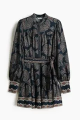 Vestido corto de estilo túnica en color azul marino con estampado paisley, cuello mao, mangas largas con puños anchos abotonados y un cinturón lazada ajustable a la cintura.