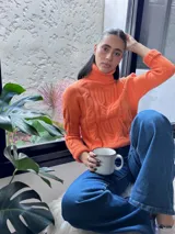 Suéter tejido de punto trenzado color salmón, con cuello alto y mangas largas. Corte ajustado al cuerpo.