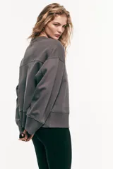 Buzo gris oscuro, de corte oversized y tejido liviano de algodón, con hombros caídos y cuello redondo ribeteado.