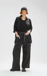 Camisa de manga corta color negro, confeccionada en popelín de algodón, con silueta oversize y dos bolsillos frontales, uno con solapa y otro con ojal y botón.