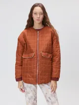 Campera reversible capitoneada con cierre frontal. Un lado es de color negro y el otro es de color beige, ambos con diseño acolchado. Cuenta con cuello redondo, mangas largas y bolsillos laterales.