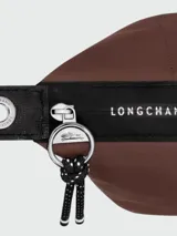 Cartera de mano Longchamp modelo Le Pliage Energy tamaño S, confeccionada en lona de color bordó con detalles en cuero negro. Cuenta con doble asa superior, correa de hombro ajustable y extraíble, cierre principal con cremallera y solapa frontal con broche a presión.