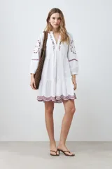 Vestido midi blanco con bordados de flores en el escote, mangas y ruedo.