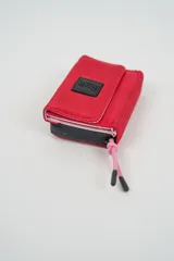 Billetera plegable color naranja con cierre de velcro y detalle de cordón marrón en el lateral. Presenta un parche negro con texto en relieve en la solapa frontal.