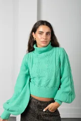 Polera de punto color verde menta, con cuello alto, mangas globo y diseño de trenzas en el frente.