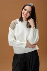 Sweater de punto color beige con cuello redondo y detalles de parches en cuero sintético blanco en los hombros. Presenta mangas largas con puños acanalados y un corte holgado.