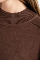 Vestido corto de punto color marrón, con cuello alto, mangas largas con puños acanalados y ruedo acanalado. Presenta un diseño de corte recto y holgado.