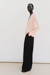 Pantalón de tiro alto y pernera ancha, color marrón, con pinzas delanteras, bolsillos frontales y cierre con cremallera y botón.