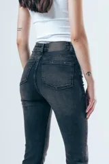 Jean de corte skinny y tiro medio, confeccionado en denim elástico de color gris oscuro con efecto lavado. Presenta diseño clásico de cinco bolsillos, cierre frontal con botón y presillas en la cintura.