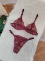 Conjunto de lencería compuesto por un corpiño triangular y una bombacha tipo tanga, ambos confeccionados en encaje bordó con detalles de terminaciones en satén.