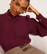 Camisa celeste de crepé con cuello inglés, manga larga abullonada y abotonadura frontal.