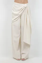Pantalón beige de pierna ancha, confeccionado en tela suave con finos destellos dorados, diseño forrado y sobre tela drapeada a modo de cinturón.
