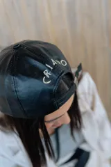Gorra tipo béisbol de cuero sintético negro, con diseño minimalista y ajuste posterior metálico.