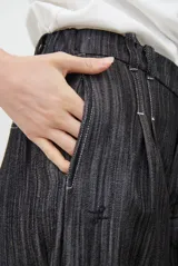 Pantalón de jean azul oscuro de tiro alto, con diseño holgado de pierna ancha, pinzas en la cintura y costuras a la vista.