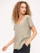 Remera blanca de poliéster y algodón, con escote en V, corte relajado, bordes sin rematar, detalles de costura central expuesta y dobladillo estilo camisero.