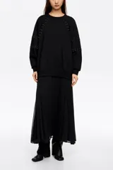 Vestido largo de estilo casual, confeccionado en tejido tipo sudadera color negro. Presenta cuello redondo, mangas largas con detalles de remaches metálicos en los hombros y brazos, y una falda plisada de corte amplio.