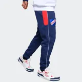 Pantalón de jogging Umbro del Club Nacional de Football, color azul marino. Presenta el escudo del club en el muslo derecho y el logo de Umbro en el izquierdo, ambos bordados. Incluye cordón ajustable en la cintura y detalles de líneas blancas laterales.