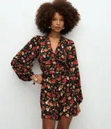 Enterito corto de viscosa con estampado floral sobre fondo negro, escote en V, mangas largas con volumen y puños ajustados.